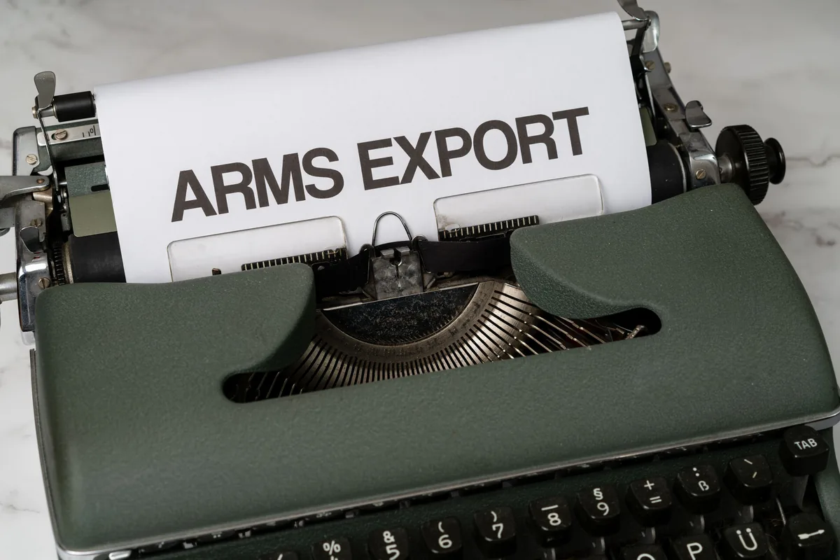 Close-up of a vintage typewriter with the text Arms Export on paper, focusing on journalism and government topics.